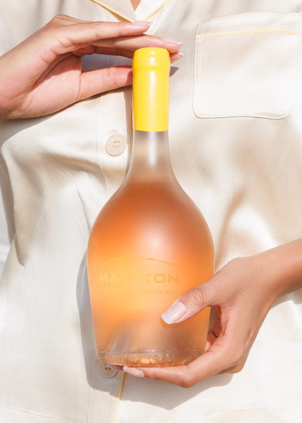 A person holds a frosted bottle of Hanikon Côtes de Provence Rosé, highlighting the bottle's elegant design. The image emphasizes the premium quality of Hanikon's rosé, perfect for special occasions and sophisticated settings.