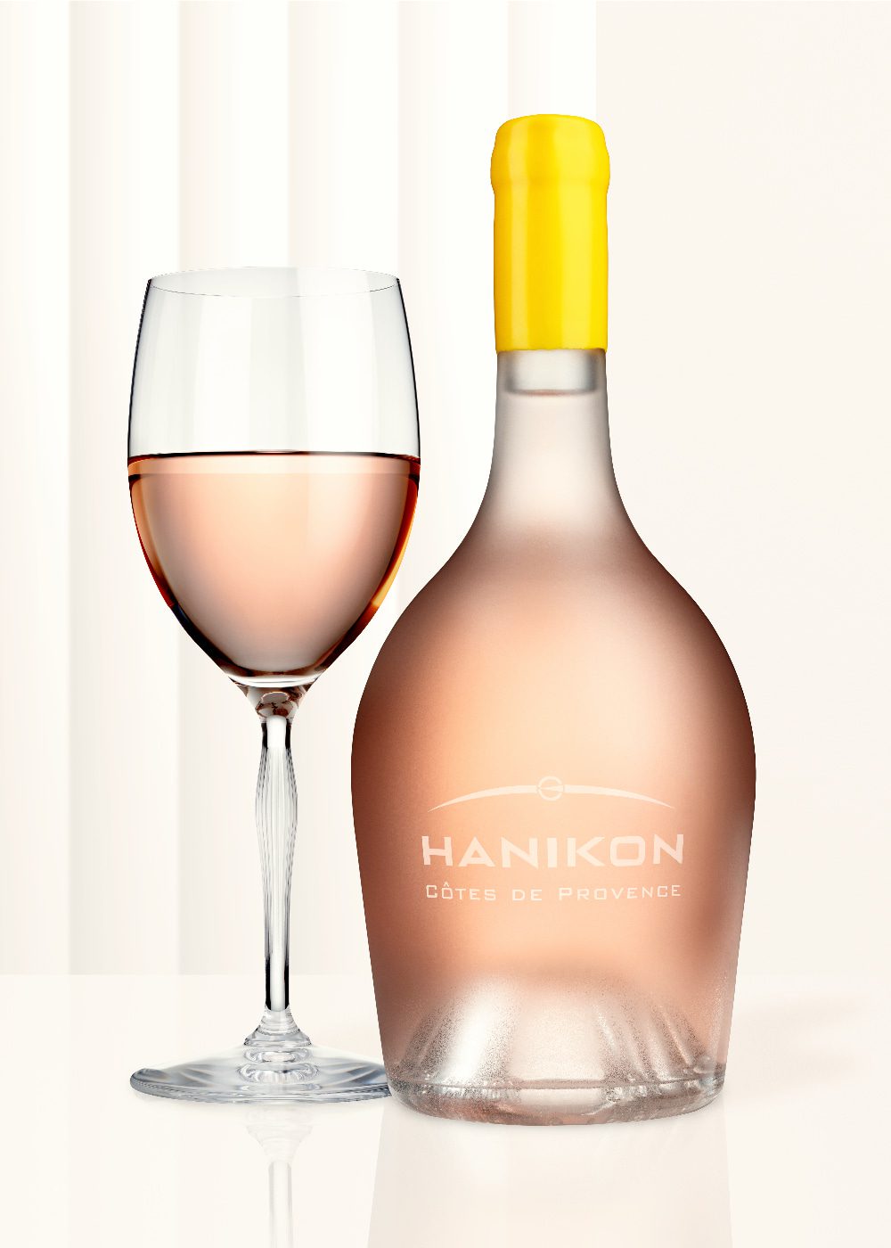 A sleek bottle of Hanikon Côtes de Provence Rosé paired with a filled wine glass, set against a minimalist background. The elegant design of the frosted bottle and the pale pink hue of the rosé wine reflect Hanikon's dedication to quality and sophistication.